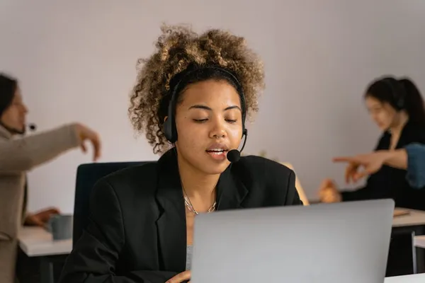 A Singapore customer service agent on a headset, calm posture, taking notes while handling a complaint call in a quiet workstation