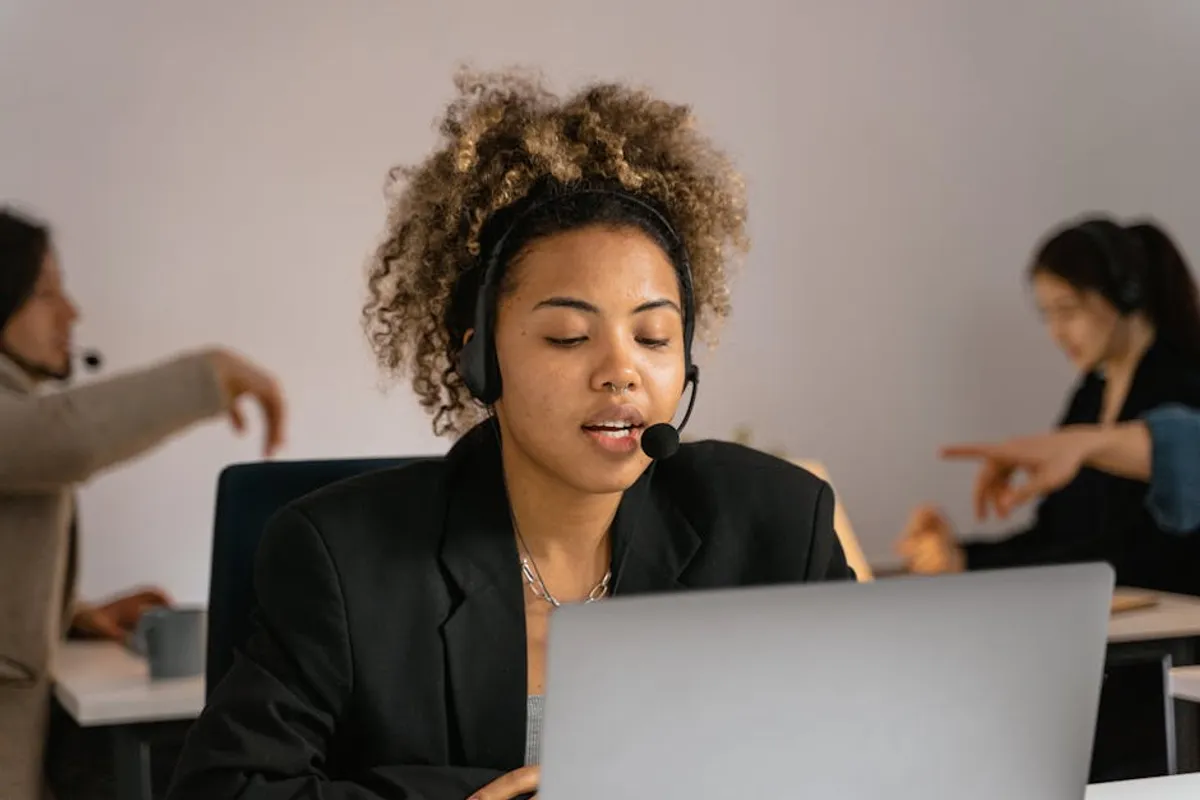 A Singapore customer service agent on a headset, calm posture, taking notes while handling a complaint call in a quiet workstation