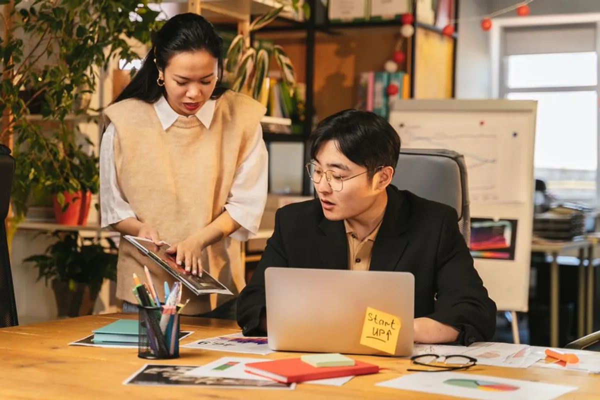 A Singapore professional preparing a structured status update on a laptop, with bullet points visible, calendar showing weekly cadence