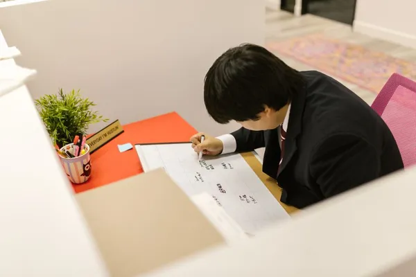 A Singapore professional planning their week at a desk with a paper planner, laptop calendar visible, coffee, in a calm focused workspace