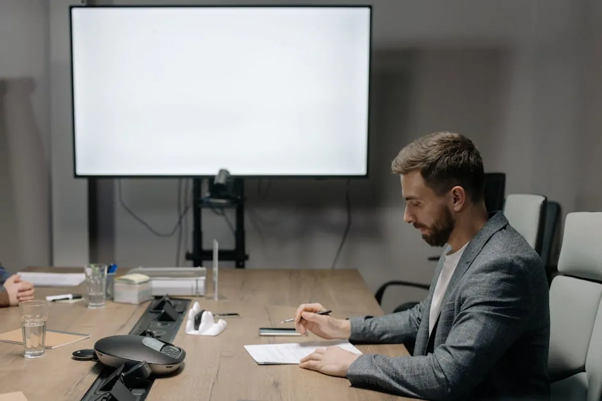 A Singapore professional preparing notes at a desk before walking into an important meeting — laptop open with an agenda, a printout, and a coffee on a clean desk