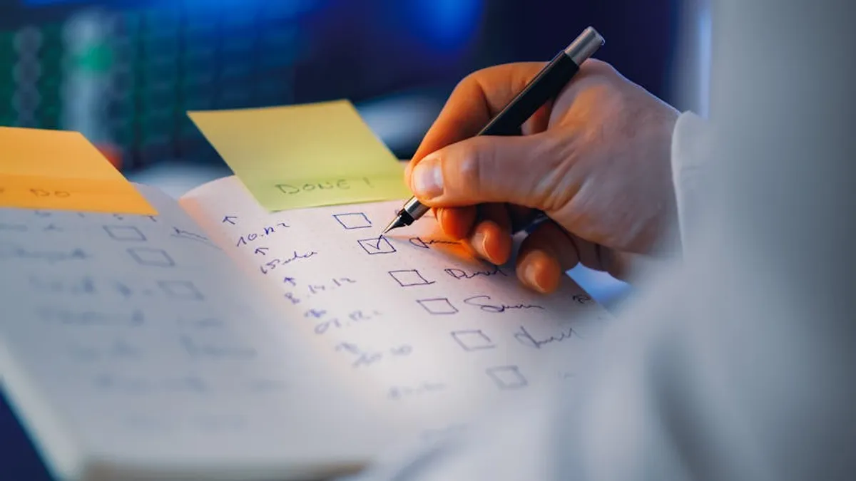 A Singapore professional triaging tasks on a paper notebook at a desk in the morning, with three priorities circled and a calendar visible