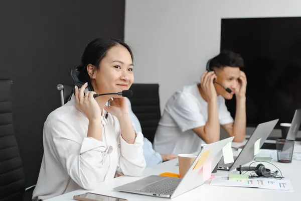 A Singapore customer service professional carefully composing a reply to a difficult customer email at a desk, paused mid-thought