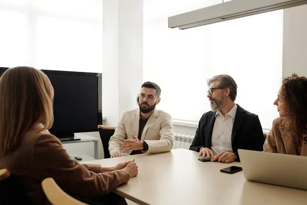 A Singapore professional in a polite but firm conversation with a colleague at a desk, calm posture, gestures suggesting clear boundaries