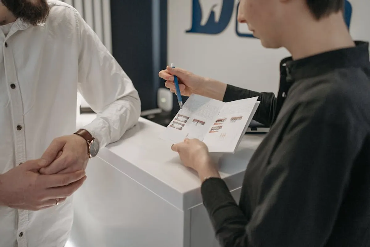 A Singapore customer service professional speaking calmly with a customer at a service counter — both standing, conversation focused, evident respect on both sides