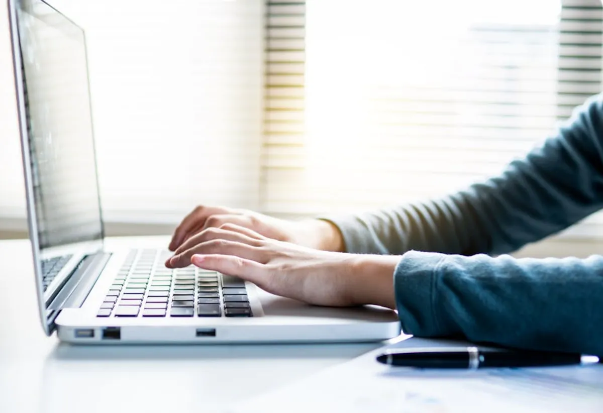 A professional in a Singapore office composing an email at a laptop, with the email draft visible on screen