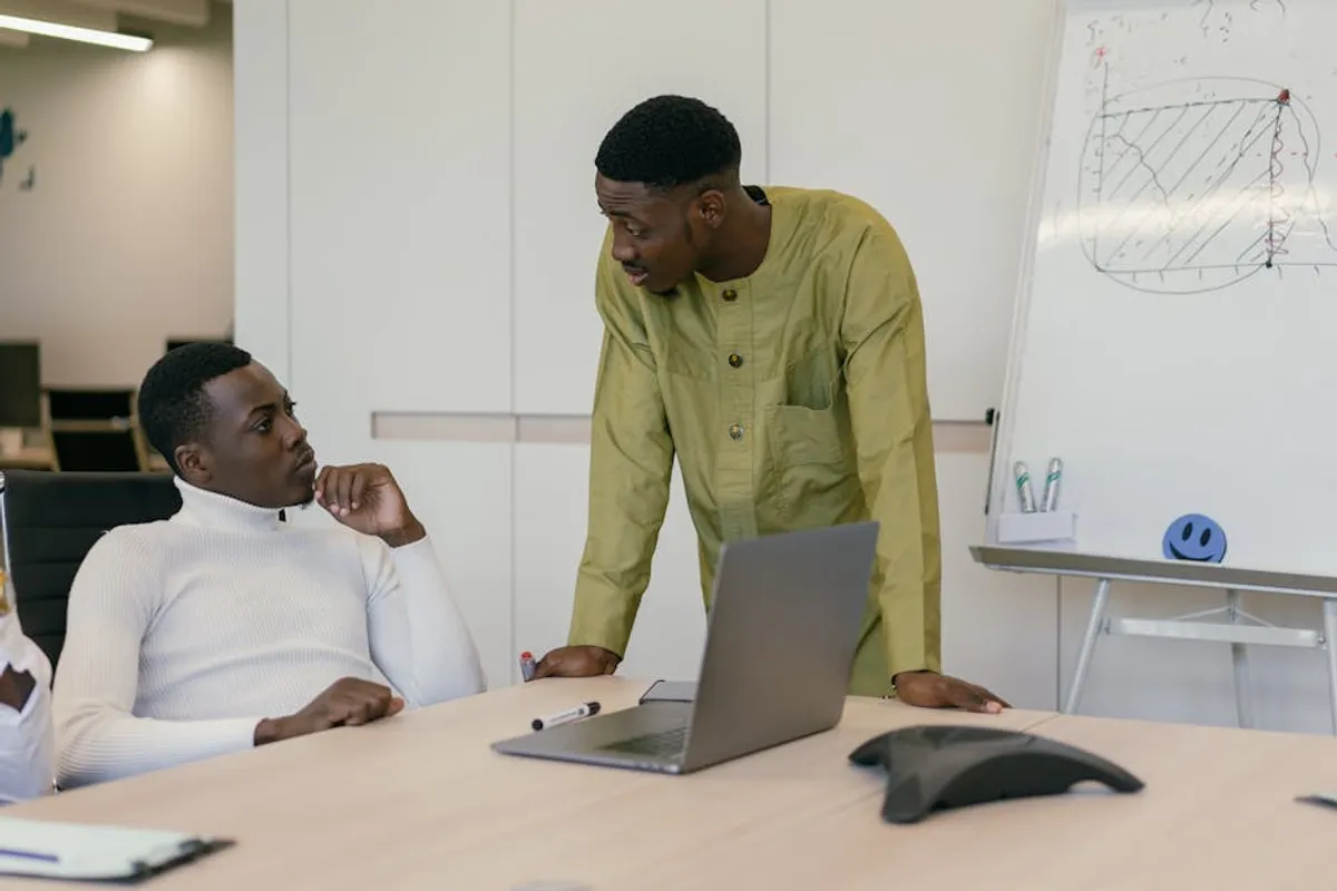 Two Singapore professionals in a focused face-to-face conversation in a meeting room, attentive listening posture, clear engagement