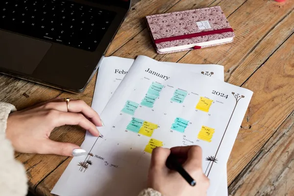 A Singapore professional reviewing a colour-coded weekly calendar with distinct time blocks visible, organised laptop view of focus and admin slots